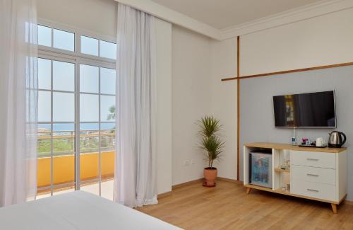 a bedroom with a bed and a tv and a window at Melia Jardines del Teide - Adults Only in Adeje