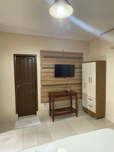 Canaã dos CarajásにあるHOTEL QUALITY PLUSのテレビ、テーブル、冷蔵庫が備わる客室です。