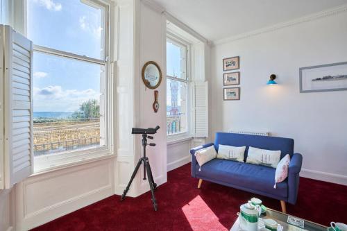a living room with a blue couch and a window at Host & Stay - The Aquamarine Weymouth Beach in Weymouth
