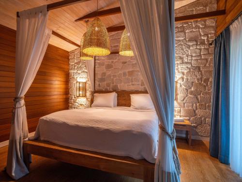 a bedroom with a bed and a stone wall at Kimera Lounge Boutique Hotel & Spa in Cıralı