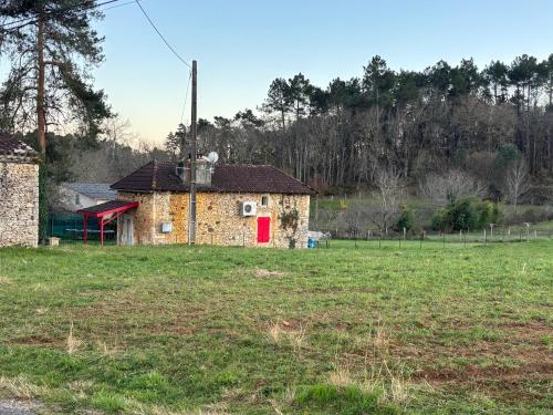 an old building with a red door in a field at Gîte de Raynal in Les Junies