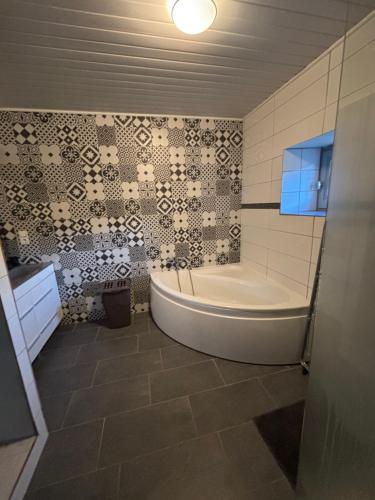 a bathroom with a tub and a tile wall at Gîte de Raynal in Les Junies