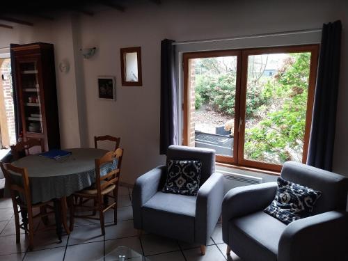 un salon avec une table et des chaises et une fenêtre dans l'établissement Les Noisettes Sauvages proche Etretat, à Villainville