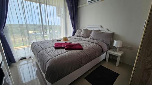 een slaapkamer met een bed met een groot raam bij Sunset view studio at 777 Beach Condo in Ban Mai Salae