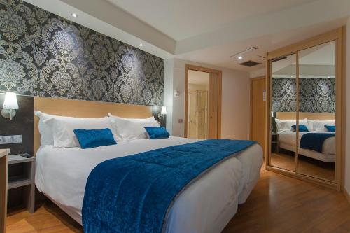 a hotel room with a large bed with a blue blanket at Sercotel Codina in Donostia-San Sebastián