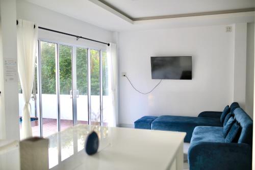 a living room with a blue couch and a sliding glass door at The Munique Cliff House Chumphon - private jacuzzi with beach views in Chumphon