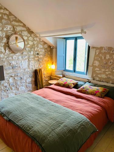 une chambre avec deux lits et un mur en pierre dans l'établissement L'écrin de verdure, à Ligré