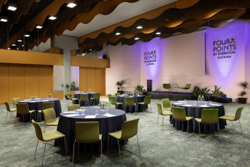 a banquet hall with round tables and yellow chairs at Four Points by Sheraton Catania Hotel in Catania