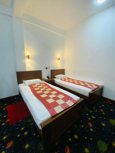two beds in a room with a checkered blanket at Heritage Grand - Badulla in Badulla