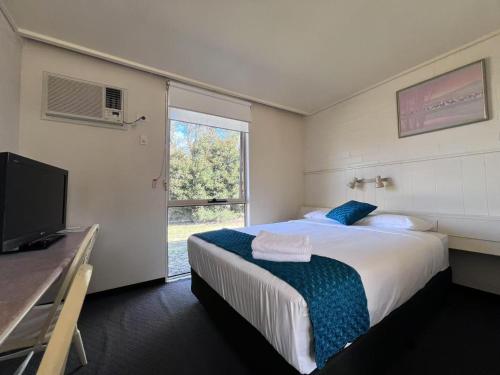 a bedroom with a large bed and a television at Leongatha Motel in Leongatha