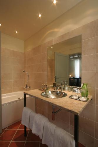 a bathroom with a sink and a tub and a mirror at Hostellerie et la parenthese uzes in Uzès
