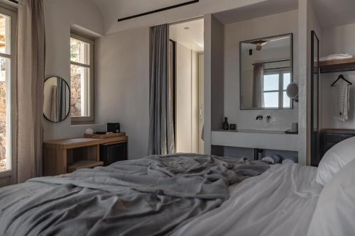 a bedroom with a bed and a sink and a mirror at Stamna Sifnos a member of Design Hotels in Sifnos