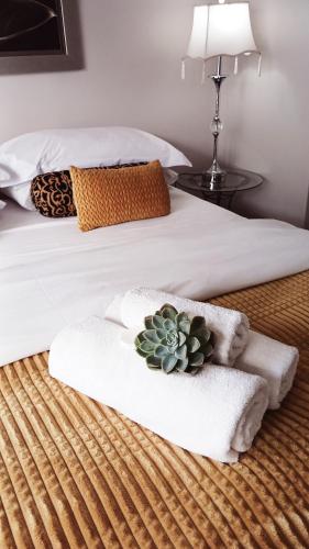 a bed with two towels and a cactus on it at Lamon Guesthouse in Kroonstad