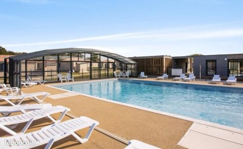 une piscine avec des chaises longues et un bâtiment dans l'établissement Chalet sur la côte Landaise, à Saubrigues
