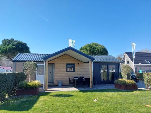 a house with a table and chairs in a yard at Strandcamping Valkenisse in Biggekerke