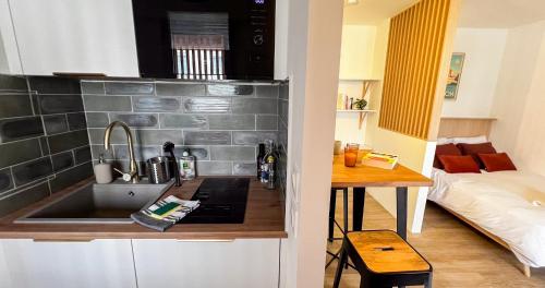 - une cuisine avec un évier et une table avec un lit dans l'établissement Parking Included - CLIM - Terrace - Hypercentre, à Avignon