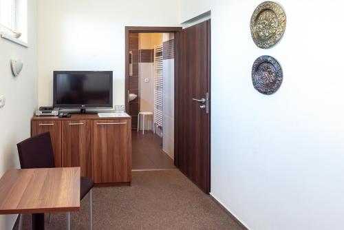 a room with a television and a table and a door at Penzion Na Dlouhé in Uherské Hradiště