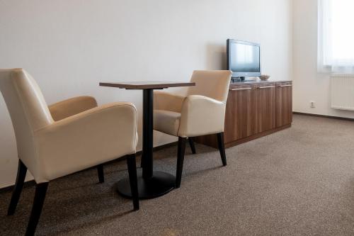 a room with a table and two chairs and a television at Penzion Na Dlouhé in Uherské Hradiště