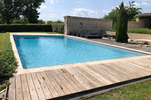 une piscine avec une terrasse en bois à côté d'une maison dans l'établissement Douceur de Vivre Évasion Familiale au Vert, à Beaumont-du-Périgord