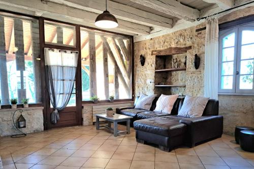 - un salon avec un canapé en cuir et quelques fenêtres dans l'établissement Douceur de Vivre Évasion Familiale au Vert, à Beaumont-du-Périgord