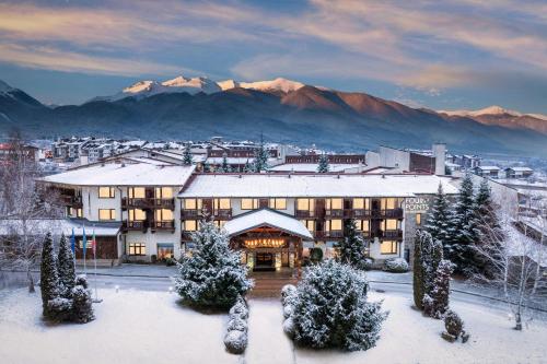 a hotel in the snow with mountains in the background at Four Points by Sheraton Bansko in Bansko