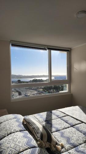 a bedroom with a bed and a large window at Departamento Concepción in Concepción