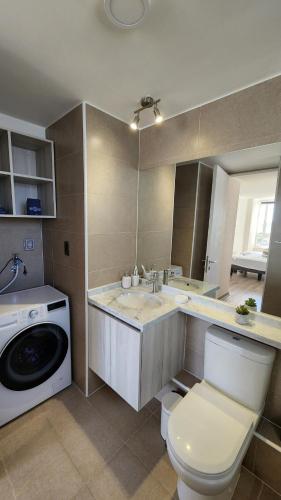 a bathroom with a toilet and a sink and a washing machine at Departamento Concepción in Concepción
