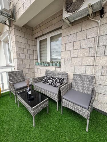 three chairs and a table on a patio with grass at Sobe i Apartman R Bileća in Bileća
