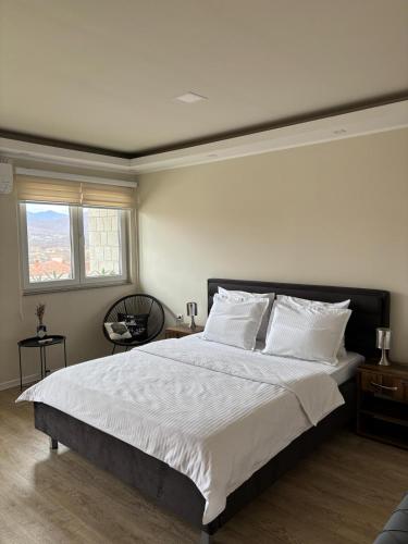 a bedroom with a large bed with white sheets and a window at Sobe i Apartman R Bileća in Bileća