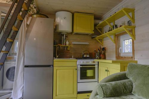 a kitchen with yellow cabinets and a refrigerator at Metai mikeA year in the forest in Paliepis