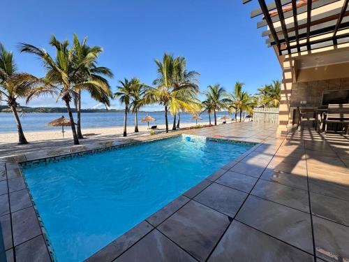 a swimming pool next to a beach with palm trees at Luxurious Beachfront house-Villa 44 in Gueima