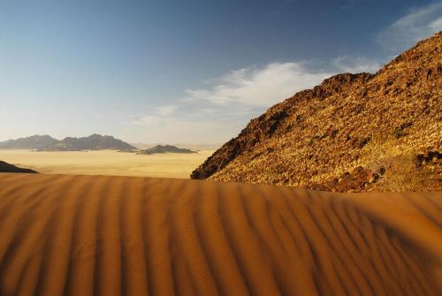a sand dune in the desert with mountains in the background at Le Mirage Resort & Spa in Sesriem