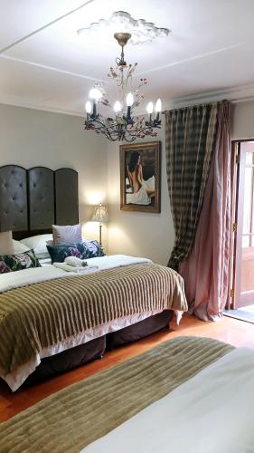 a bedroom with a large bed and a chandelier at Lamon Guesthouse in Kroonstad