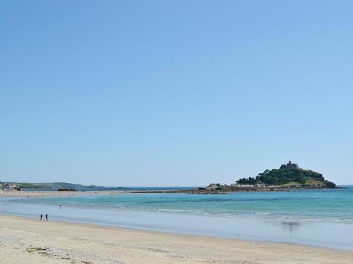 a beach with people walking on the sand and the ocean at The Paddock in Saint Hilary