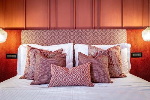 a bed with a bunch of pillows on it at Hotel Duomo Firenze in Florence