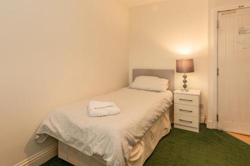 a small bedroom with a bed and a night stand at Ricky Road Guest House - Budget in Watford