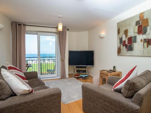 a living room with two couches and a flat screen tv at 8 Belvedere Court in Paignton