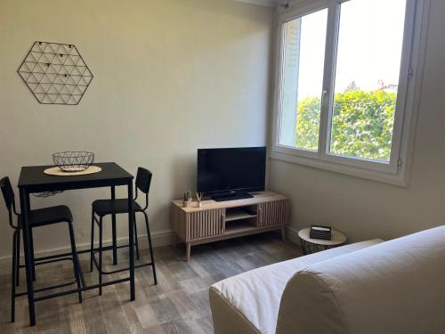 Camera con tavolo, TV e letto di Petit appartement cosy Miribel a Miribel