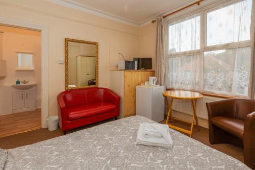 a room with a bed and a red chair and a window at Ricky Road Guest House - Budget in Watford