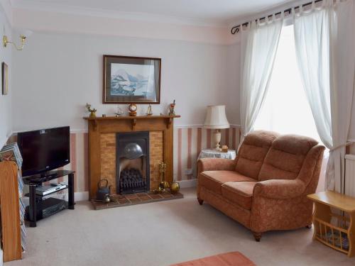 a living room with a chair and a fireplace at Daisy Bank Cottage in Bowness-on-Windermere