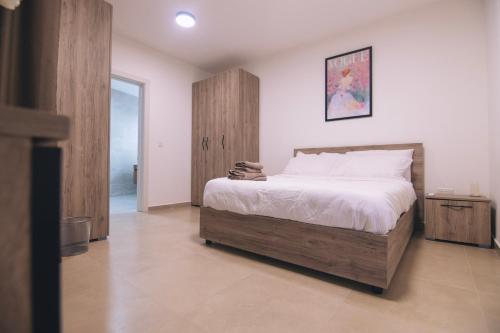 a bedroom with a large bed and a wooden cabinet at The Valley Collection - Suite B3 in Xagħra