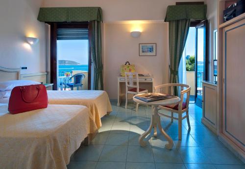 um quarto de hotel com duas camas e uma mesa com uma cadeira em Parco Aurora Terme em Ischia