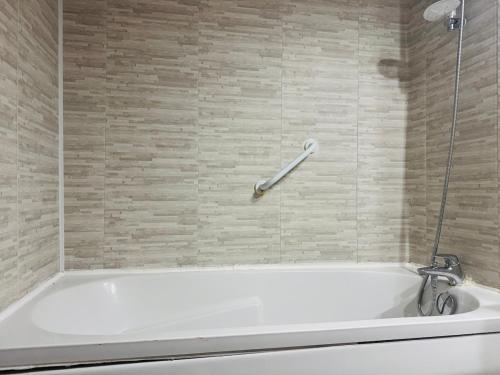 eine weiße Badewanne in einem Badezimmer mit einer Wand in der Unterkunft Cozy apartment near thermal baths in Balaruc-les-Bains