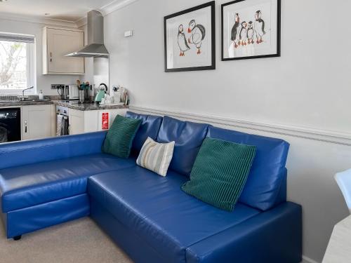 a blue couch in a living room next to a kitchen at Puffins in Port Isaac