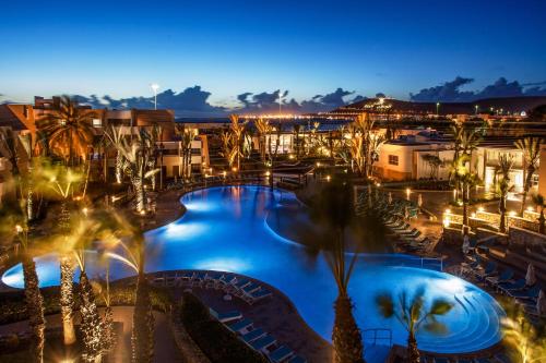 a resort with a large pool at night at Dunes d'Or Ocean Club in Agadir