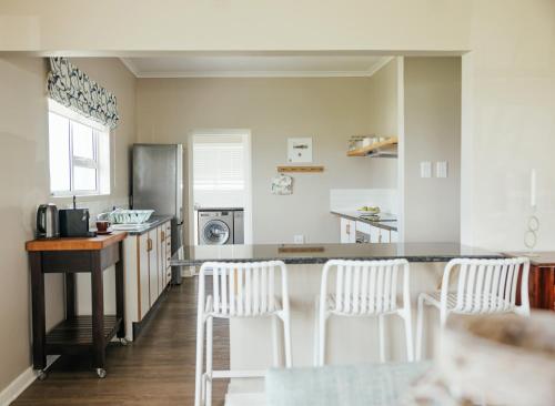 a kitchen with white chairs and a counter top at Seal Point Lighthouse in Cape St Francis
