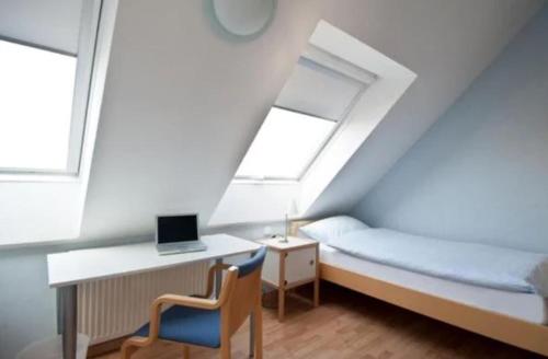 a bedroom with a bed and a desk with a laptop at Haus Blinkfüer in Wangerooge
