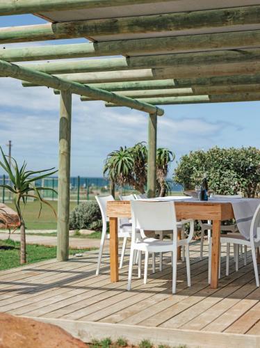 a wooden table and chairs on a deck with the ocean at Seal Point Lighthouse in Cape St Francis