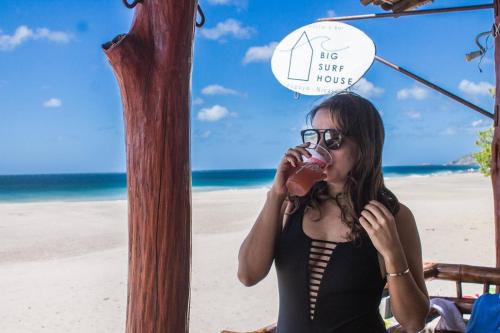 a woman sitting on the beach eating a doughnut at Big Surf House in Popoyo