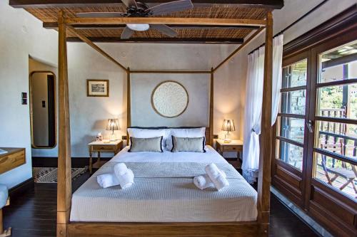 una camera con letto a baldacchino e cuscini bianchi di Pelion Luxury Villa Ivy ad Áno Vólos